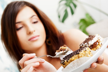 Young beautiful woman with a cake. Closeup portrait. Sitting on sofa at her homeの写真素材