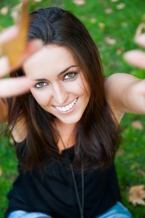 Portrait of smiling young girl sitting on grass in the forest and looking at youの写真素材