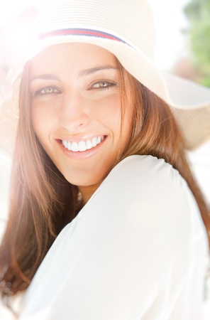 Closeup portrait of a beautiful young woman having a happy thought outdoor in summer park looking at cameraの写真素材