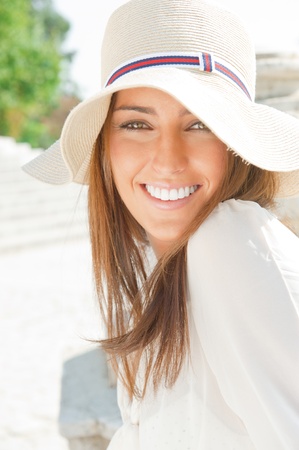 Closeup portrait of a beautiful young woman having a happy thought outdoor in summer park looking at cameraの写真素材
