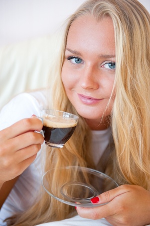 Closeup portrait of a pretty young female having a cup of coffee at hotel roomの写真素材