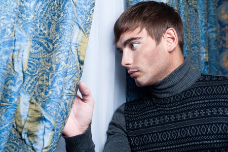Side view of young business man looking through glass windowの写真素材