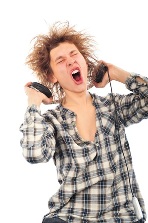 Portrait of funny young man with awesome hairdo isolated on white background. Listening music using headphonesの写真素材