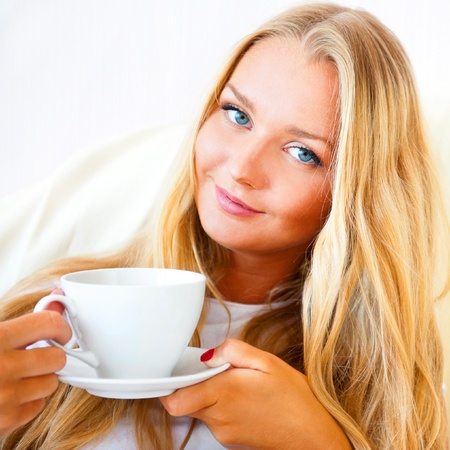 Young woman at home sipping tea or coffee from a cupの写真素材