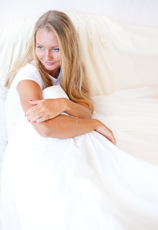 Young blond woman enjoying a sunny morning in bed. Vertical Shotの写真素材
