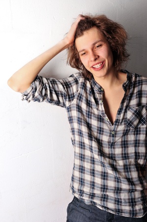 Handsome man with funky hairstyle casually leaning against the wallの写真素材