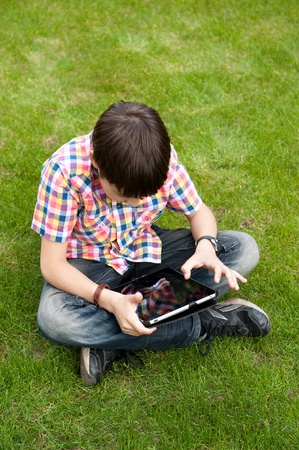 Young boy outdoors on the grass at backyard using his tablet computer. Educating and playingの写真素材