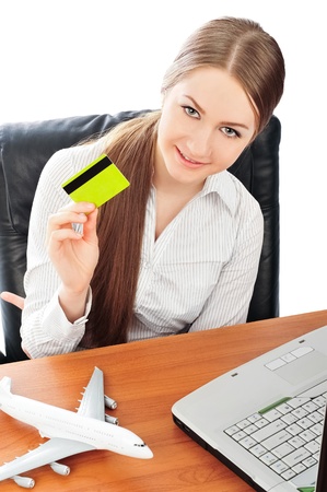 Closeup portrait of young pretty woman at her workplace holding credit card. Online tickets order conceptの写真素材