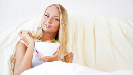 Closeup portrait of pretty caucasian woman having a healthy diet breakfast at bed. She is on vacation.の写真素材