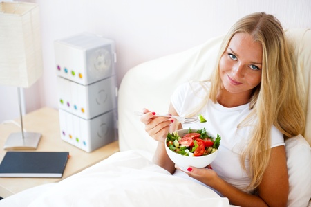Closeup portrait of pretty caucasian woman having a healthy diet breakfast at bed. She is on vacation.の写真素材