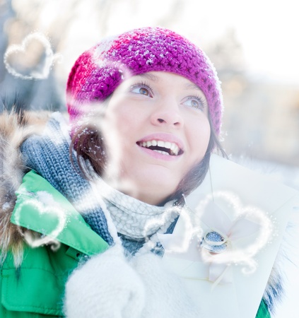 Young lady outdoors happily holding valentine gift and dreamingの写真素材