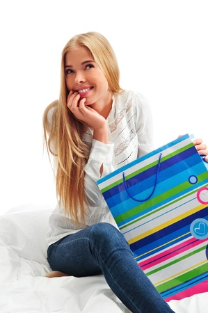 beautiful young blond woman on the bed at home with shopping bag の写真素材