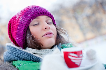 young beautiful girl day dreaming outdoors in winter while having coffeeの写真素材