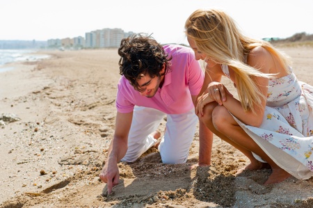 Couple in love drawing a heart in the sand while relaxing at beachの写真素材