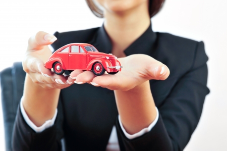 Portrait of young handsome woman holding car in her arms. Isolated on white. Insurance conceptの写真素材
