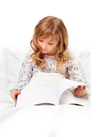Closeup portrait of adorable little girl resting in her bed with white with beautiful long curly hairの写真素材