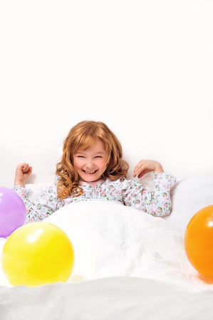 Closeup portrait of adorable little girl resting in her bed with white linenの写真素材
