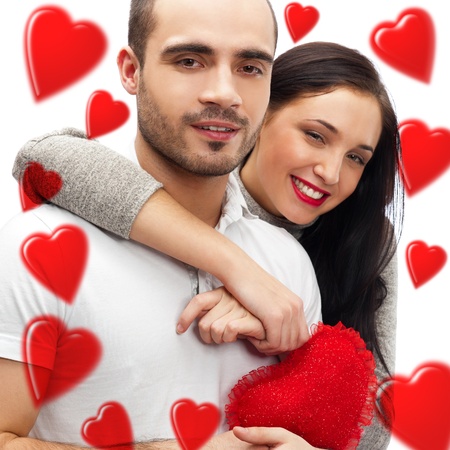 Beautiful young love couple embracing against a white background and many red hearts flying around themの写真素材