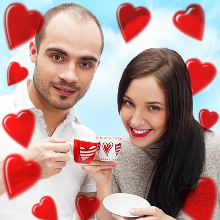 Portrait of young beautiful couple having tea or coffee beverage together at romantic backgroud with heart shapeの写真素材