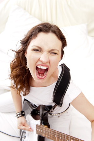 Portrait of beautiful young and attractive womanplaying her guitar at homeの写真素材