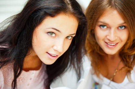 Two women whispering and smiling while shopping inside mallの写真素材