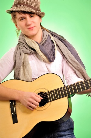 Closeup portrait of cute caucasian man playing the guitar over green backgroundの写真素材