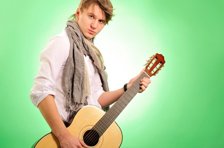 Closeup portrait of cute caucasian man playing the guitar over green backgroundの写真素材
