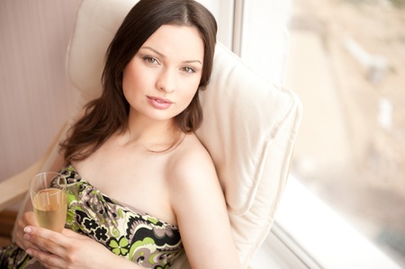 Portrait of smiling beautiful young brunette woman at home drinking wine. Horizontal shotの写真素材