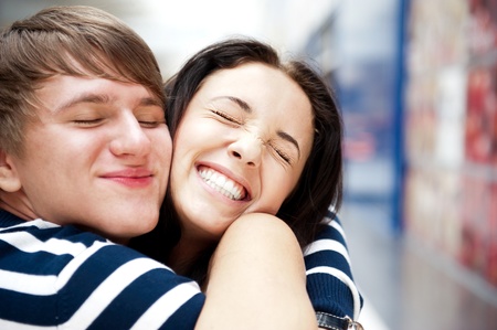 Young man meeting his girlfriend with opened arms at airport arrival hallの写真素材