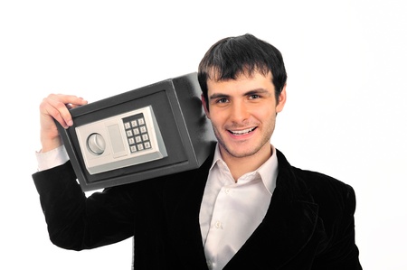 Portrait of young businessman holding metal safe. He looks confident and happyの写真素材