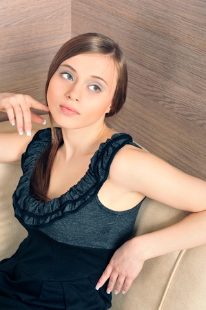Portrait of young fashionable calm woman sitting relaxed on couch and looking at the right side of the shotの写真素材