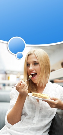 Portrait of young pretty smiling woman eating cake at shopping mall cafe  Blank graphic balloon with her thoughts with lots of copyspace for your text and logo overheadの写真素材