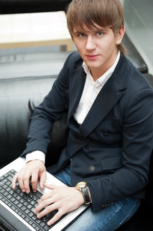 Portrait of handsome young man working with laptop at cafe at business center hallの写真素材