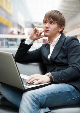 Portrait of handsome young man working with laptop at cafe at business center hallの写真素材