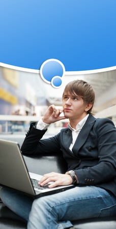 Portrait of handsome young man working with laptop at cafe at business center hall. Blank graphic balloon with his thoughts overheadの写真素材