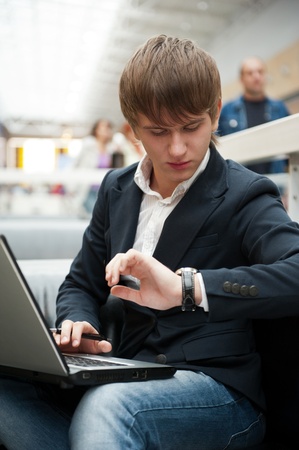 Portrait of handsome young man working with laptop at cafe at business center hallの写真素材