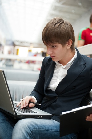 Portrait of handsome young man working with laptop at cafe at business center hallの写真素材