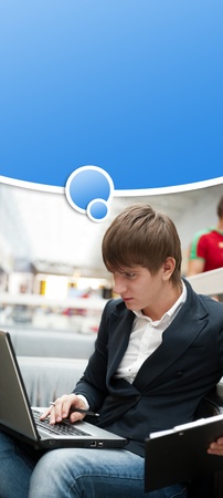Portrait of handsome young man working with laptop at cafe at business center hall. Blank graphic balloon with his thoughts overheadの写真素材