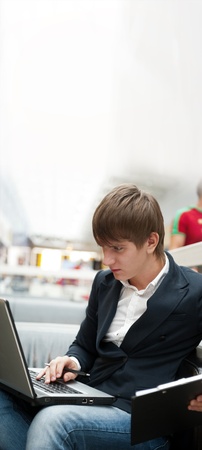 Portrait of handsome young man working with laptop at cafe at business center hall. Lots of copyspaceの写真素材