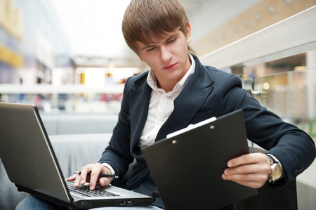 Portrait of handsome young man working with laptop at cafe at business center hallの写真素材