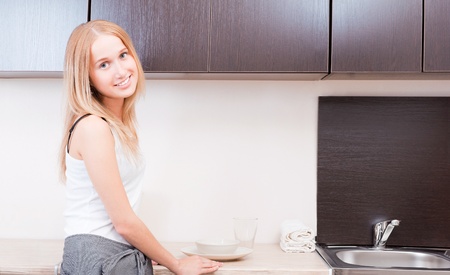 Portrait of beautiful relaxed young woman standing at the kitchen counter - Indoorの写真素材