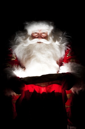 Santa sitting at the Christmas room and looking into the sackの写真素材