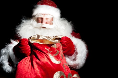 Santa sitting at the Christmas room and looking into the sackの写真素材