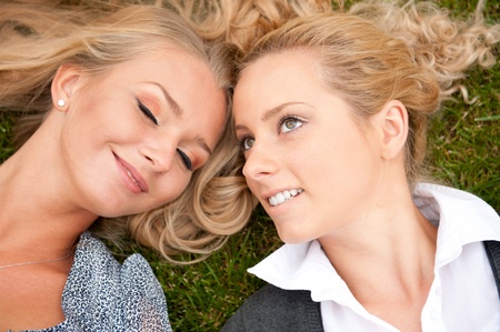 Two friended woman at park lying together relaxed and daydreamingの写真素材