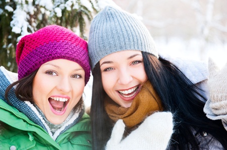 Two happy young girls having fun in winter parkの写真素材