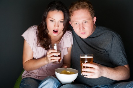 A couple watching a scary movie and it scared them so much that they are screaming.の写真素材