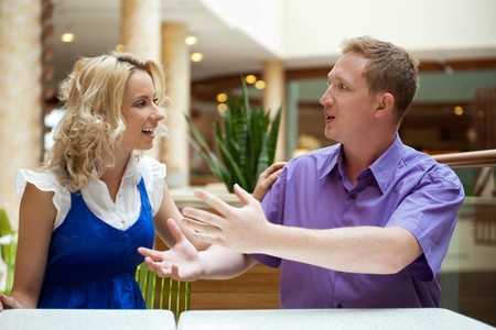 Young debating or talking couple inside mall sitting near the tableの写真素材