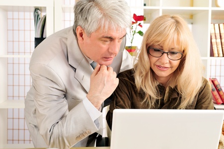 A confident smiling business woman with her colleague at modern comfortable office working using laptopの写真素材