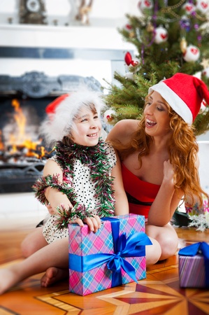 Mother and her daughter sitting together near christmas treeの写真素材
