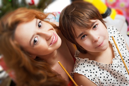 Mother and her daughter sitting together near christmas treeの写真素材